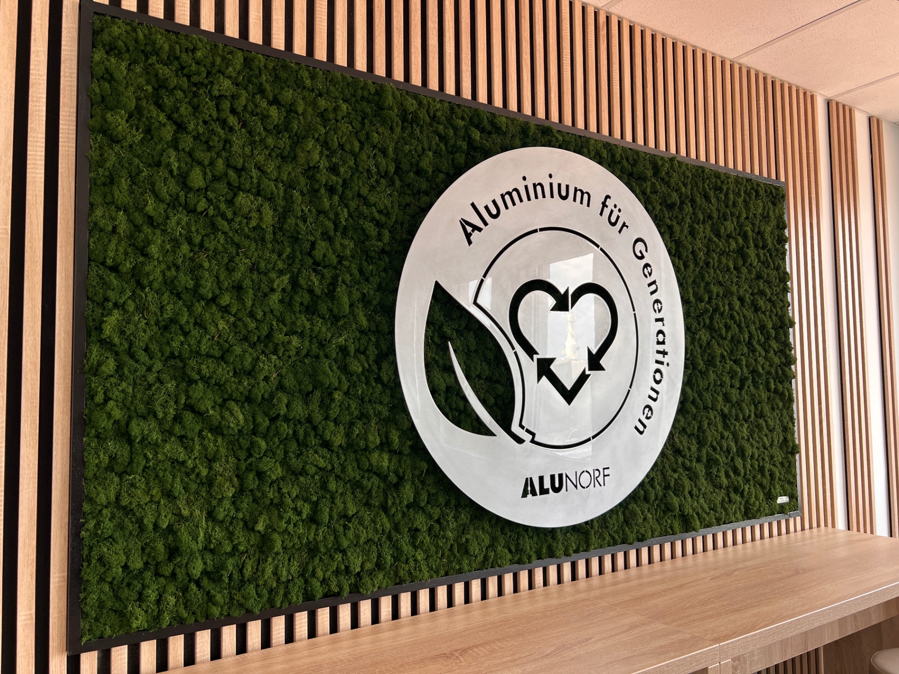 ALUNORF-Logo auf grüner Moospflanzenwand
